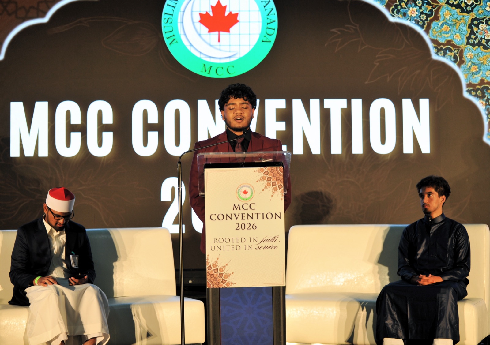 A young man presents on stage as fellow youth look on